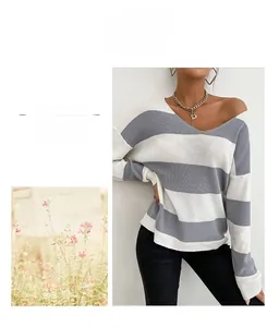 Détail du pull en maille rayé gris et blanc avec col en V et coupe décontractée