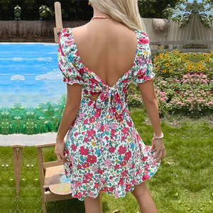 Robe d'été fleurie dos nu avec nœud et manches bouffantes dans un jardin ensoleillé
