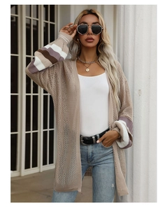 Detail of knitted cardigan showing striped cuffs and breathable crochet hollow texture