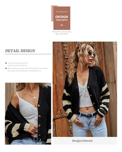 Detail of V-neck knit cardigan with gold buttons and striped cuffs on black thick fabric