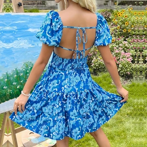 Robe fleurie bleue dos nu avec manches bouffantes et jupon à volants dans un jardin