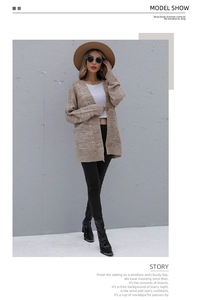 Beigefarbene Strickjacke mit Zopfmuster, weißem Top und schmaler schwarzer Hose