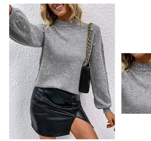 Detail of grey knit sweater showing high neck, white pearls, and puff sleeves texture