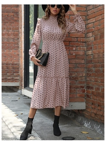 Detail of pink polka dot tiered dress with smocked bodice and ruffled cuffs on red brick wall