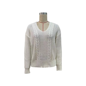 Detailed view of the classic cable knit texture and V-neckline on the white sweater