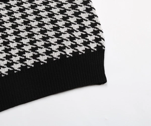 Detail of black and white houndstooth knit sweater with ribbed hem and high quality texture