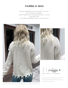 Detail of white distressed knit sweater featuring ripped hollow-out shoulder and fringe trim