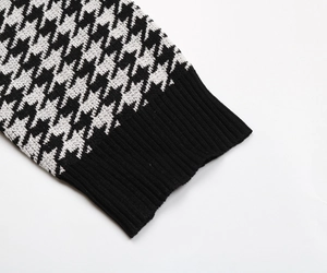 Detail of black and white houndstooth knit sweater with ribbed cuffs and fine stitching