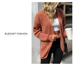 Detail of chunky cable knit texture on an orange oversized cardigan in street style