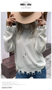 Detail of white turtleneck knit sweater with distressed cut-outs and frayed edges