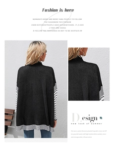Detailed close-up of a loose-fitting black knit sweater with stylish white sleeve stripes