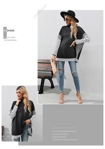Detail showing striped patchwork on the cuffs and hem of a loose black knit sweater
