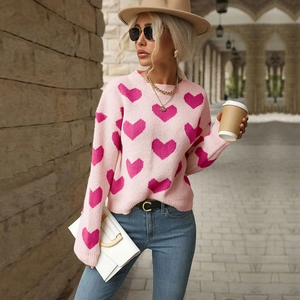 Pink knit sweater with magenta heart pattern worn with blue jeans and tan fedora hat