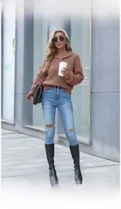 Detail of a brown waffle knit sweater paired with blue ripped jeans and black boots