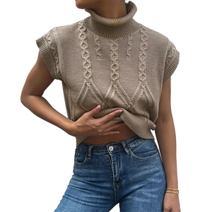 Chaleco de punto trenzado beige para mujer con cuello alto y vaqueros denim