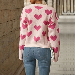 Pink women's knit sweater with heart pattern shown from a back view street style