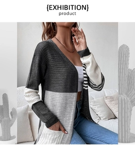 Detail of color-block knit cardigan with grey tones and striped cuffs on casual sofa