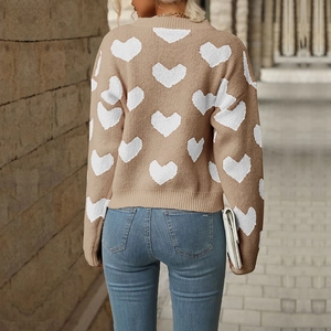 Close-up of heart jacquard pattern on brown knit sweater with ribbed cuffs and hem