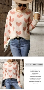 Detail of knitted beige sweater featuring pink heart jacquard patterns and round neckline