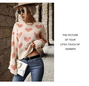 Detail of pink heart jacquard patterns on beige knitted crewneck sweater for women