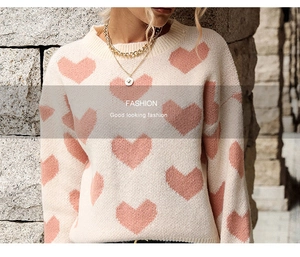 Close-up of pink heart jacquard pattern on a beige knit sweater with soft texture