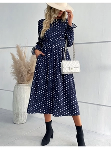 Detail of navy blue polka dot dress featuring long sleeves and elegant ruffled cuffs
