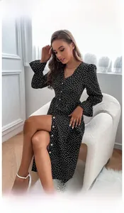 Close-up of black polka dot dress featuring a V-neckline, buttons and ruffled cuffs