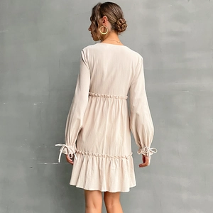 Abito beige aderente a maniche lunghe con orlo a balze e polsini con fiocco retro