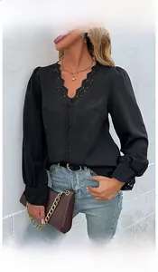 Dettaglio del bordo in pizzo sullo scollo a V di una camicia nera a maniche lunghe chic