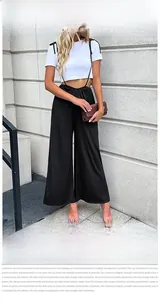Détail d'une combinaison noire à jambes larges et taille haute avec un T-shirt court blanc