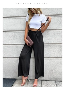 Combinaison noire chic à jambes larges portée avec un t-shirt blanc et pochette en cuir