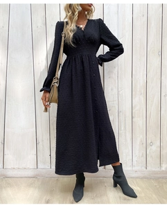 Détail d'une robe noire à col en V avec manches longues et tissu jacquard texturé