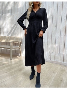 Détail d'une robe maxi noire à manches longues avec tissu texturé à pois et décolleté en V