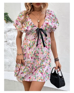 Détail de robe d'été fleurie avec décolleté en V, manches bouffantes et nœud en satin