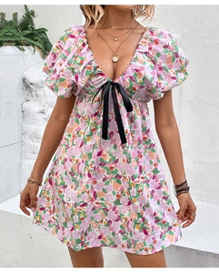 Détail d'une mini robe fleurie avec col en V, manches bouffantes et nœud noir