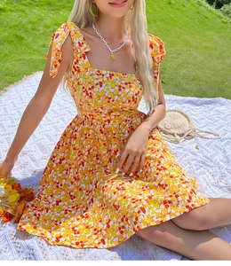Detailed view of summer floral mini dress with yellow pattern and bow shoulder straps