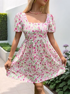 Détail de mini robe fleurie rose avec décolleté carré et manches bouffantes dehors