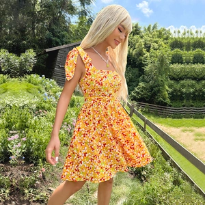 Summer yellow floral mini dress with bow shoulder straps and a square neckline on grass