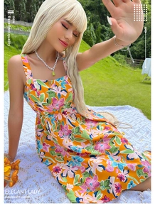 Detail of vibrant orange floral dress with pink and blue blossoms on a summer picnic blanket