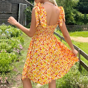 Summer yellow floral mini dress with bow straps and elastic waist in garden setting