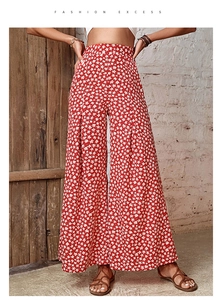 Detailed macro view of the pleated high waist and floral pattern on red wide-leg trousers