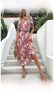 Detail of a red V-neck floral summer dress with a brown woven belt and straw handbag