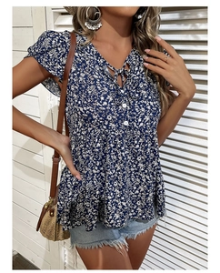 Detailed view of V-neckline with ties and white buttons on a floral summer blouse