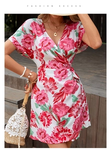 Detail of floral wrap dress with deep V-neck and waist tie on a sunny wooden stairs