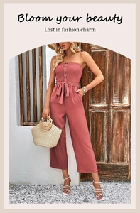 Detail of mauve strapless jumpsuit with buttons and a bow belt in a sunny outdoor setting