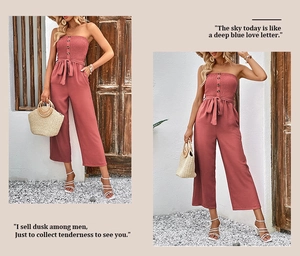 Detail view of brick red strapless jumpsuit featuring button front and belted wide-leg style