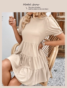 Detail of the tiered beige summer dress featuring pleated puff sleeves and texture