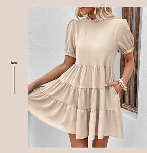 Close-up of beige tiered dress featuring a ruffled high neck and functional side pockets