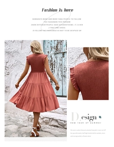 Détail de la robe à étages corail avec épaules à volants et tissu plissé élégant