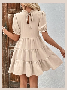 Detail of beige tiered dress showing back tie collar and elegant ruffle short puff sleeves